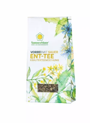 MycoVital_ Eine weiß-grüne Packung mit der Aufschrift SonnenMoor Ent-Tee Kräutermischung mit botanischen Abbildungen von Blättern und Blüten und einem kleinen durchsichtigen Fenster, in dem getrocknete Kräuter zu sehen sind.